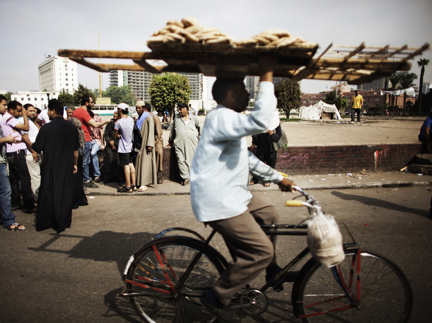 An Egyptian man delivering bread rides through Cairo's Tahrir Square last year. Couriers are taking great risks as they work around Egypt's capital.