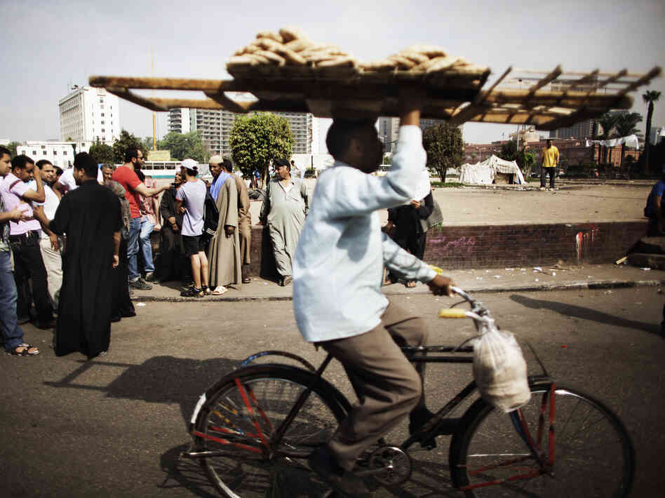An Egyptian man delivering bread rides through Cairo's Tahrir Square last year. Couriers are taking great risks as they work around Egypt's capital.