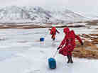 Kyrgyz girls slide plastic jugs back to their family's camp after chopping a hole in a frozen spring to fetch water. Men handle herding and trading; much of the hard labor of daily life falls to the females. Kyrgyz girls slide plastic jugs back to their family's camp after chopping a hole in a frozen spring to fetch water. Men handle herding and trading; much of the hard labor of daily life falls to the females.