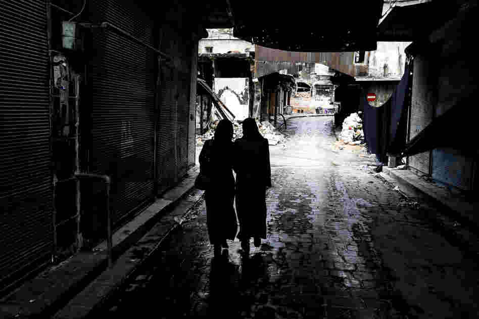 Syrian women walk through a market area in the northern city of Aleppo last November. A new website is documenting the use of rape in the Syrian conflict.