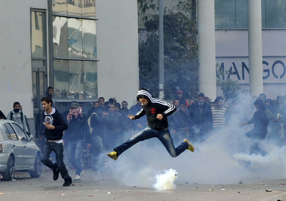 A Tunisian protester jumps amid smoke after police fired tear gas during a rally outside the Interior ministry to protest after Tunisian opposition leader and outspoken government critic Chokri Belaid was shot dead.