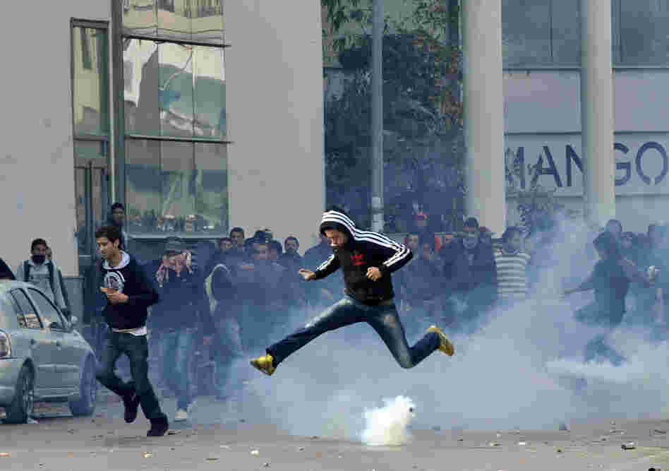 A Tunisian protester jumps amid smoke after police fired tear gas during a rally outside the Interior ministry to protest after Tunisian opposition leader and outspoken government critic Chokri Belaid was shot dead.