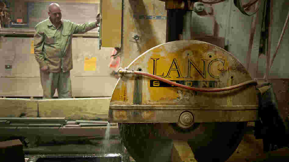 An employee uses a wet saw to cut a slab of sandstone at a Lang Stone Co. facility in Columbus, Ohio, in January. Using water while cutting helps keep dust out of the air. An employee uses a wet saw to cut a slab of sandstone at a Lang Stone Co. facility in Columbus, Ohio, in January. Using water while cutting helps keep dust out of the air.