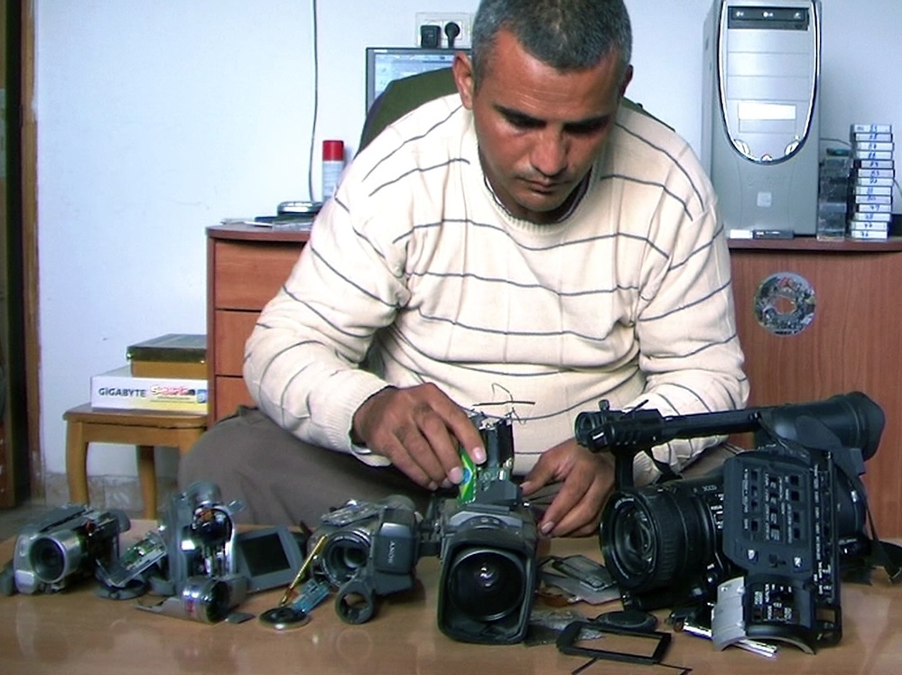 Co-director Emad Burnat examines his five broken cameras.