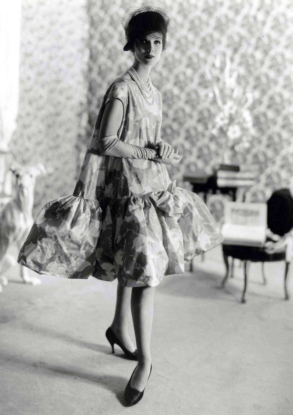 Balenciaga debuted his baby doll dress in 1958. Blume writes, "all women benefited — and benefit still — from the principal achievement of [Balenciaga's] 1950s lines: the elimination of a tight nipped-in waist and the smoother, more yielding silhouette."