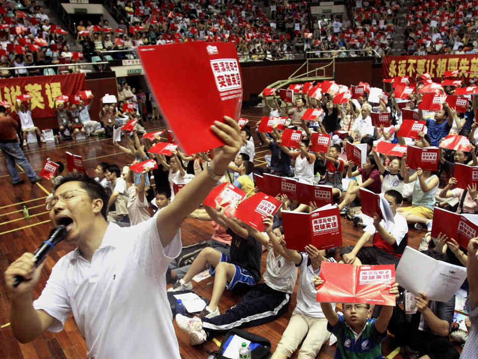 Li Yang teaches English to several thousand students attending a class at a stadium in Guangzhou, China, in 2004. His "Crazy English" technique — based on learning through shouting — draws huge crowds. In interviews, he has admitted physically attacking his wife.