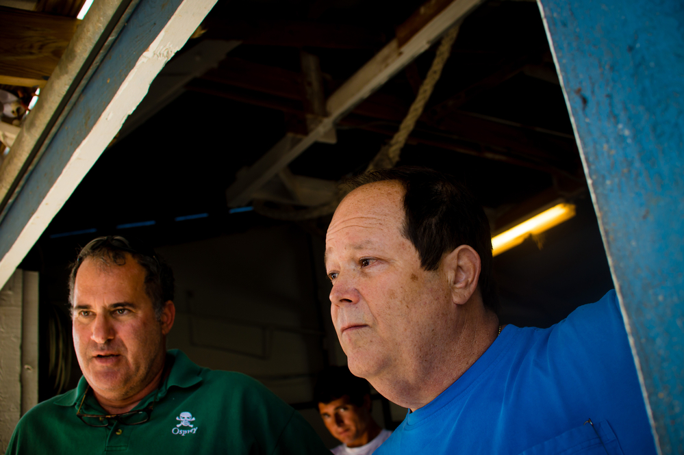 Day Boat Seafood co-owners Scott Taylor (left) and Howard Bubis watch workers unload thousands of pounds of catch from a long-line boat that was out for 10 days at their boathouse in Fort Pierce, Fla.