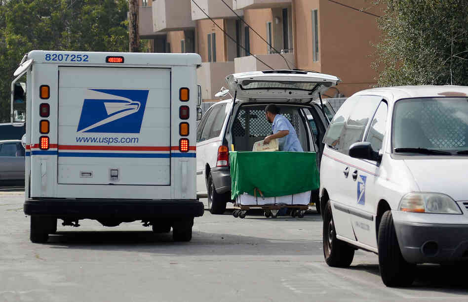 A U.S. Postal service employee loads his van as he prepares to leave the loading dock to deliver mail from the Los Feliz Post Office in Los Angeles.