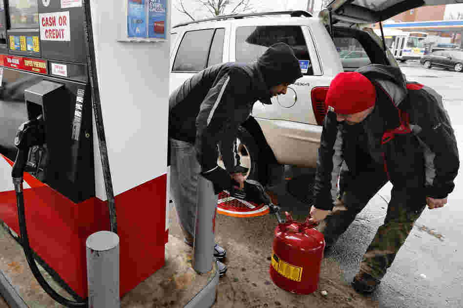 Men fill up a gas tank at a fueling station in Queens, N.Y. Blizzard warnings were in effect from New Jersey through southern Maine, with Boston expected to bear the brunt of the massive storm that could set records.