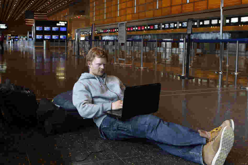 Rasmus Thomsen of Denmark works on his computer as he waits at Boston's Logan International Airport after flights were canceled or delayed.