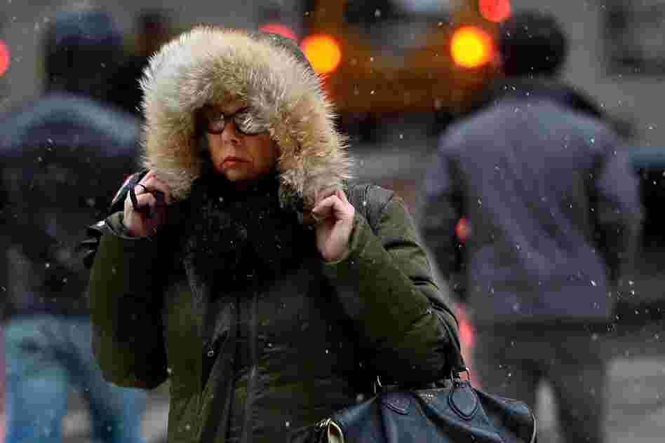Trying to stay warm, a woman in New York City clung on to her hood Friday.