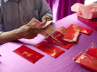 A man counts yuan to fill red envelopes in Beijing. Many families celebrate the Lunar New Year by exchanging small envelopes filled with money. A man counts yuan to fill red envelopes in Beijing. Many families celebrate the Lunar New Year by exchanging small envelopes filled with money.
