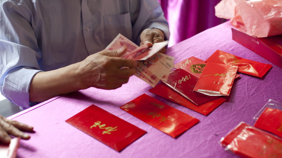 A man counts yuan to fill red envelopes in Beijing. Many families celebrate the Lunar New Year by exchanging small envelopes filled with money.
