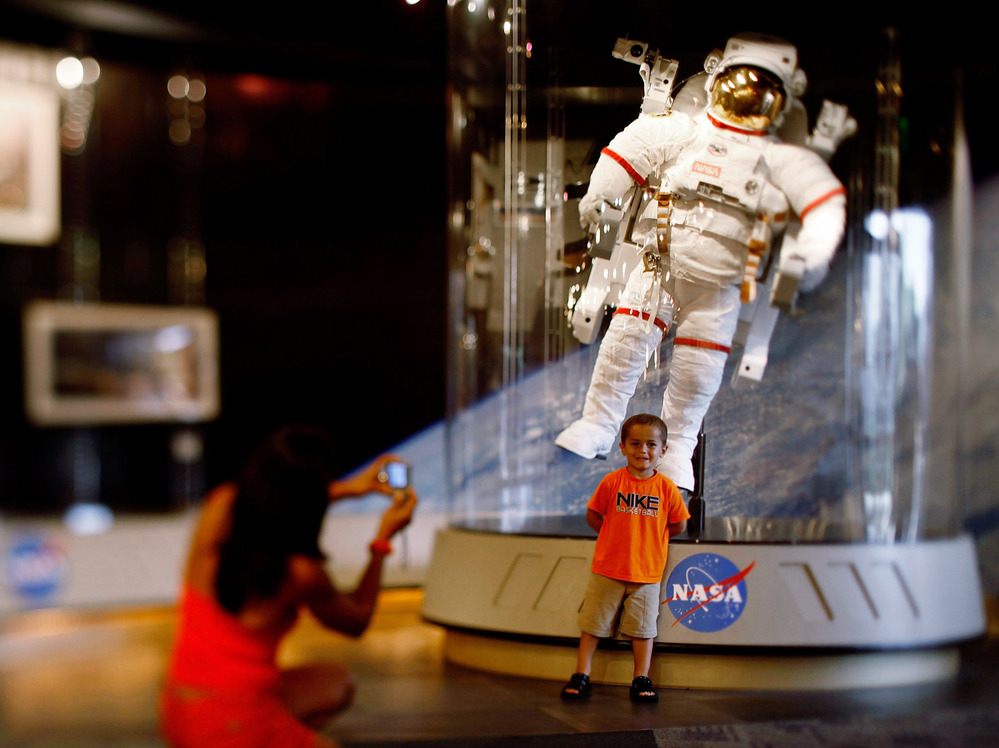 A child poses for a picture in front of an astronaut space suit at the Kennedy Space Center on the eve of the launch of Space Shuttle Endeavour July 14, 2009 in Cape Canaveral, Fla.