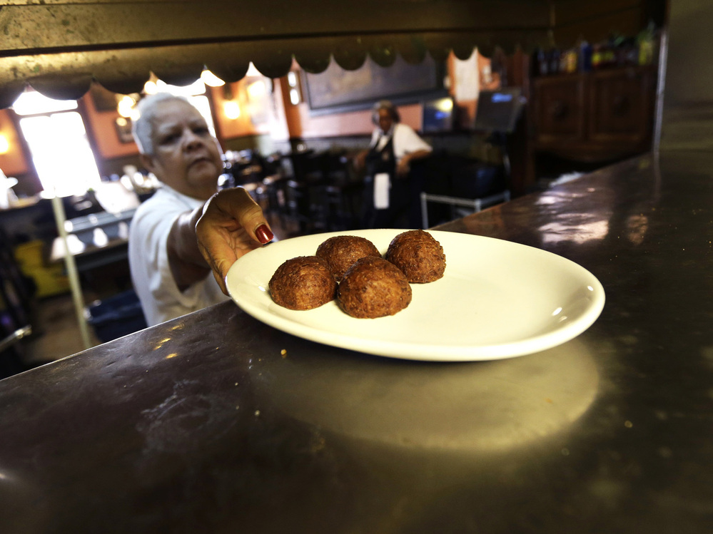 Waitress Gaynell James serves up calas cake from the kitchen at The Old Coffeepot Restaurant in the French Quarter of New Orleans on Jan. 28, 2013.