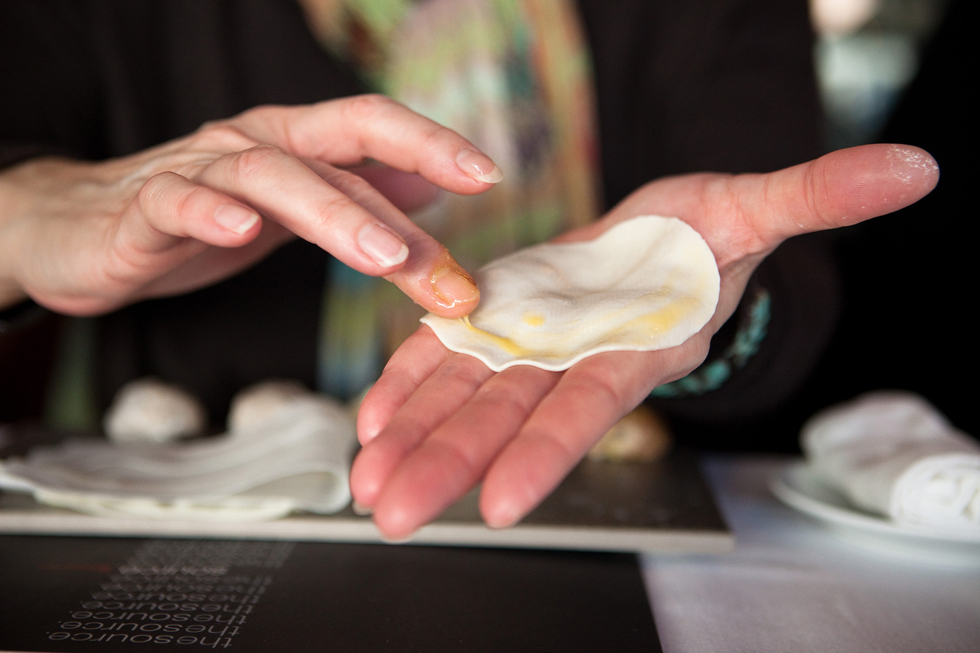 The dumpling dough circle is brushed with egg yolk in a