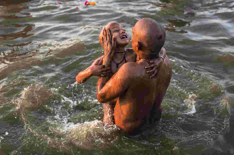 A father dips his son into the holy waters.