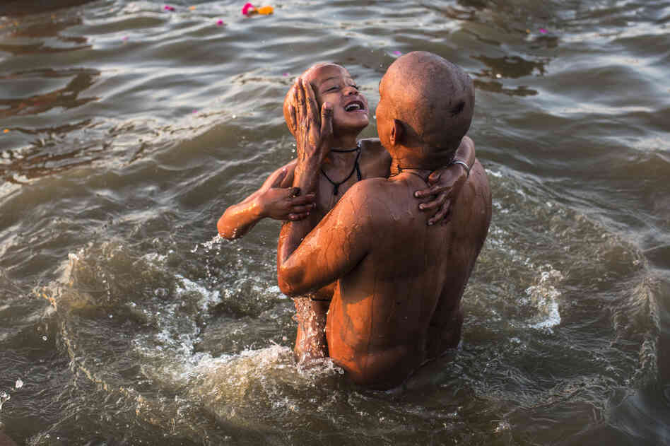 A father dips his son into the holy waters.