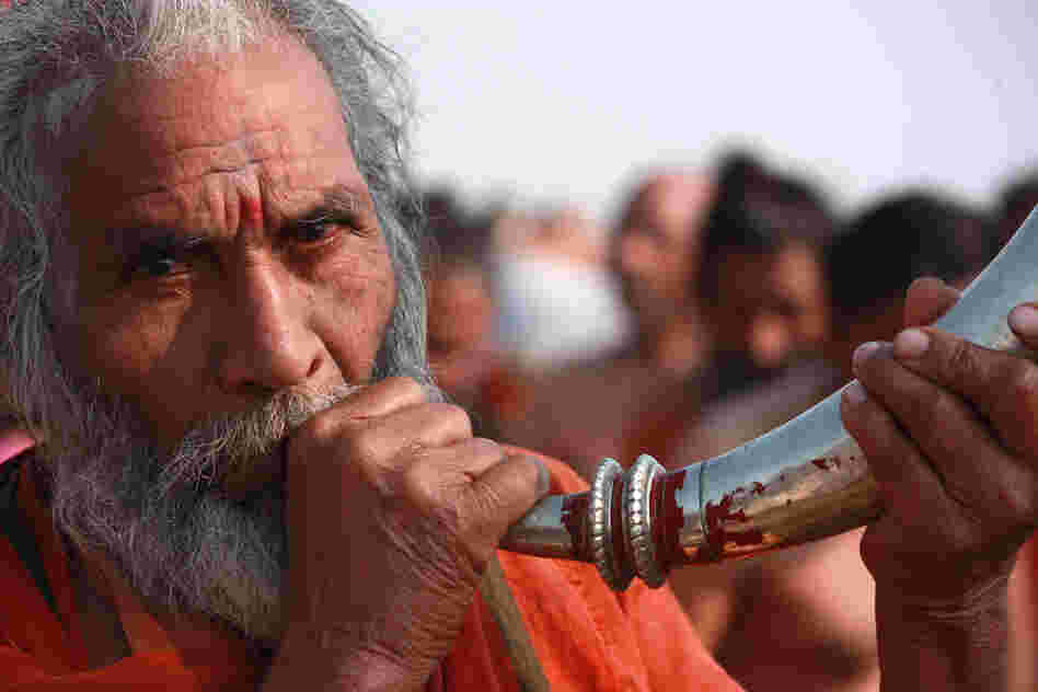 A man blows a horn in celebration during the daylong procession that drew 30 million devotees Sunday, the most auspicious day of the 55-day-long Hindu festival.