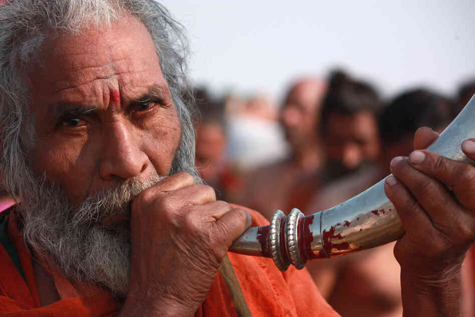 A man blows a horn in celebration during the daylong procession that drew 30 million devotees Sunday, the most auspicious day of the 55-day-long Hindu festival.