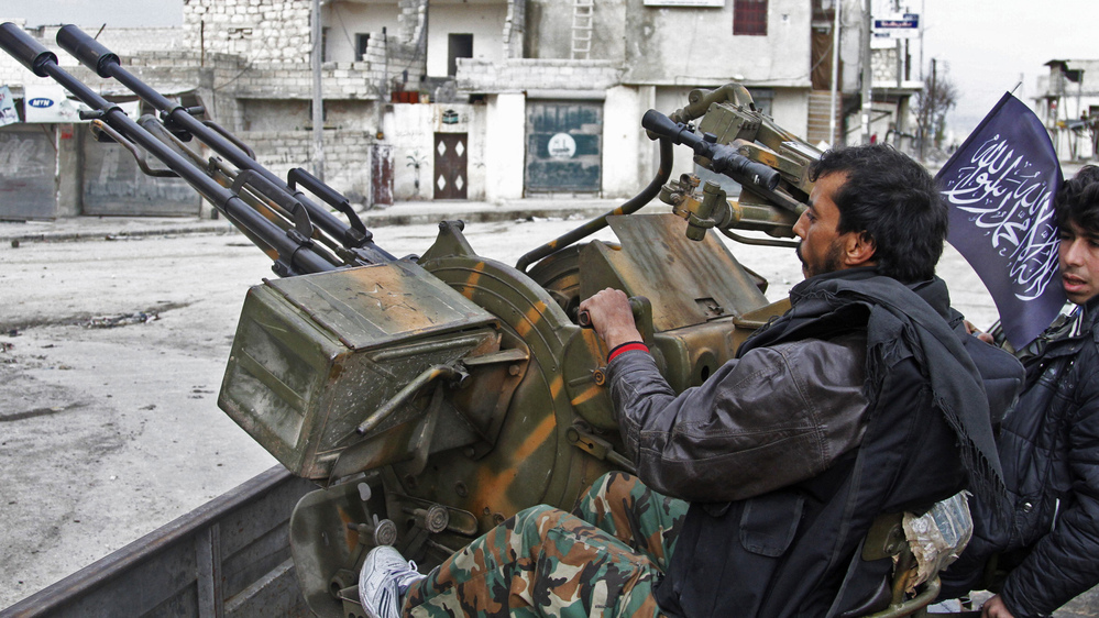Syrian rebels say they captured an important military air base in northern Syria on Tuesday. Here, rebels sit behind an anti-aircraft weapon in the northern city of Aleppo on Friday.
