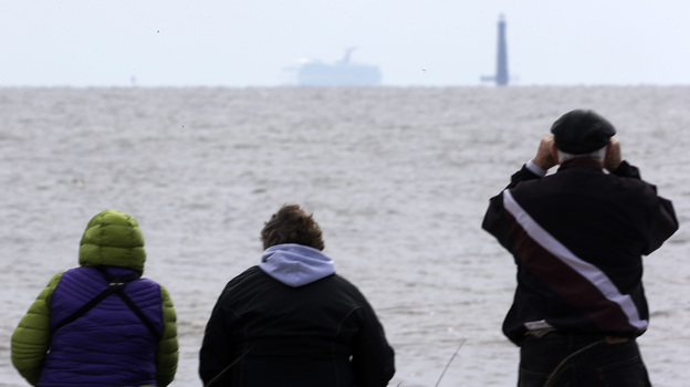 Spectators watch the Carnival cruise ship Triumph near Dauphin Island, Ala., Thursday, as the ship is towed to a terminal in Mobile. The Triumph is expected to arrive late Thursday night.