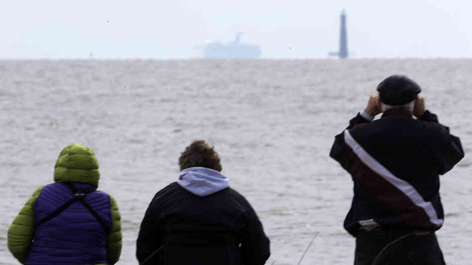 Spectators watch the Carnival cruise ship Triumph near Dauphin Island, Ala., Thursday, as the ship is towed to a terminal in Mobile. The Triumph is expected to arrive late Thursday night.