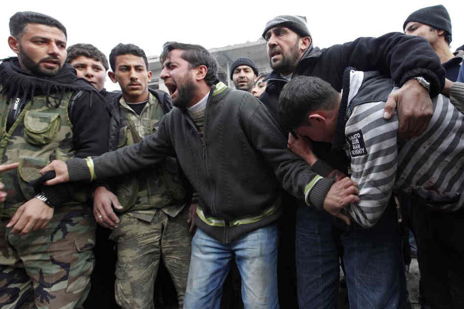 Men mourn the deaths of two of their relatives, killed by what activists said were missiles fired by a Syrian air force fighter jet from forces loyal to Syrian President Bashar Assad, at a market in Azaz, north of Aleppo, in January.