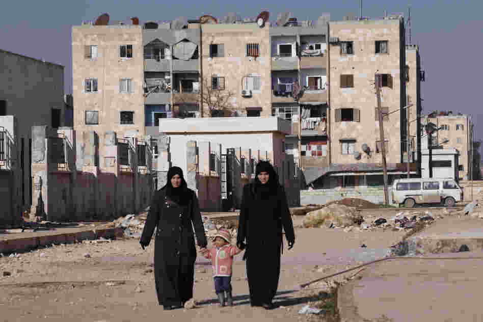 Women holding a child's hands walk along a street in Aleppo's Hanano district in January. 