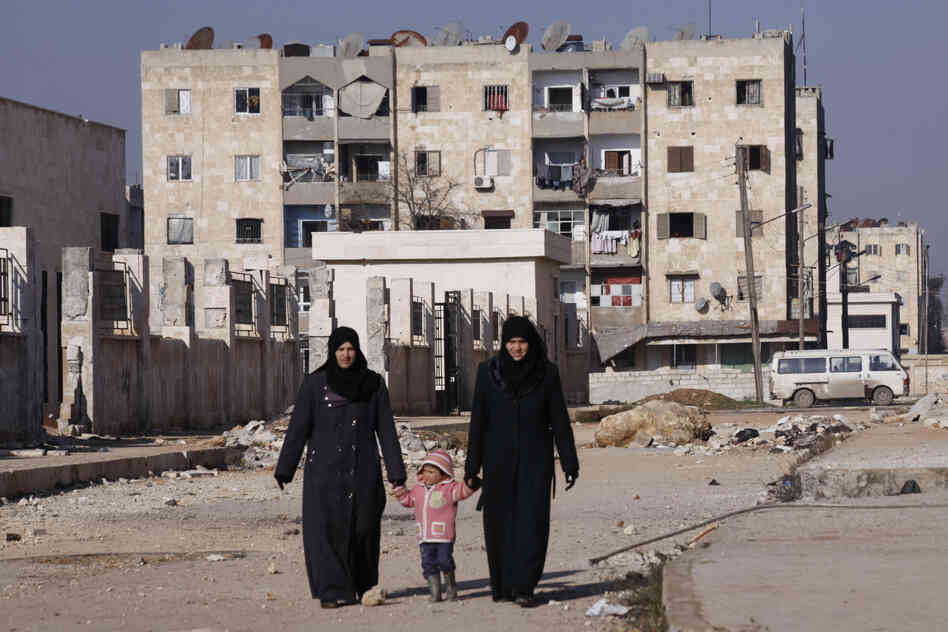 Women holding a child's hands walk along a street in Aleppo's Hanano district in January. 