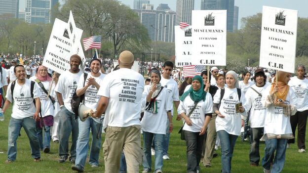 Rami Nashashibi, fourth from left, claps as he marches with IMAN leaders during a May Day immigration rally in Chicago in 2007.