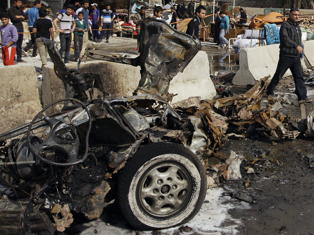 Iraqis inspect the scene of a car bomb attack in the Ameen neighborhood in eastern Baghdad on Sunday.