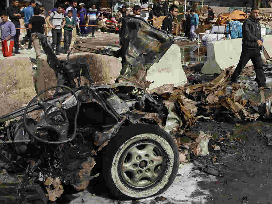 Iraqis inspect the scene of a car bomb attack in the Ameen neighborhood in eastern Baghdad on Sunday.