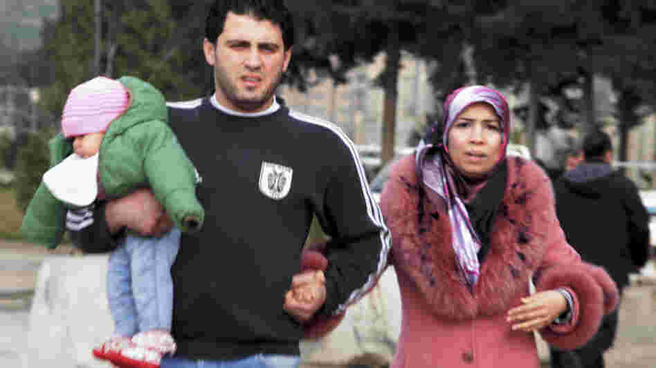 Syrian people wait at a customs gate at the Turkey-Syria border near Reyhanli, Turkey, last week. Hundreds of thousands of people are fleeing central Syria, heading to southern Turkey.