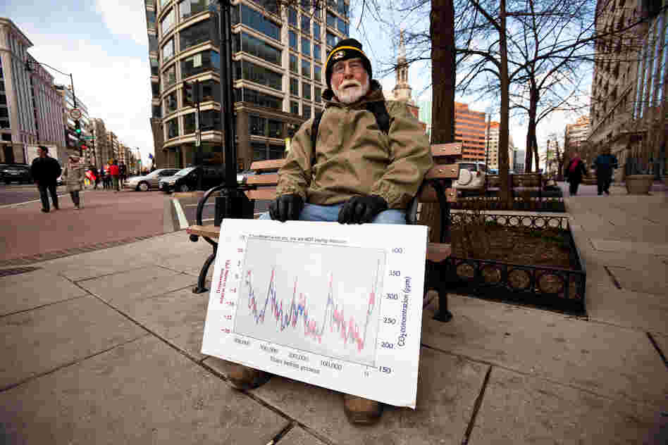 Dr. J. William Hirzy, a chemistry professor at American Universiy, rests outside the rally route with a graph he uses to teach his students about the relationship between atmospheric carbon dioxide and global temperature.