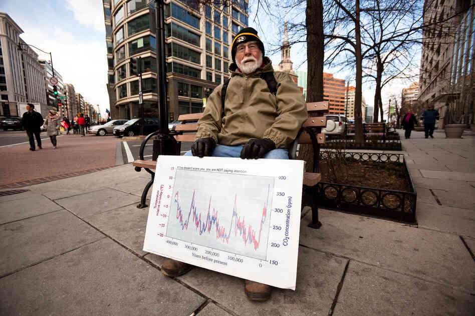 Dr. J. William Hirzy, a chemistry professor at American Universiy, rests outside the rally route with a graph he uses to teach his students about the relationship between atmospheric carbon dioxide and global temperature.