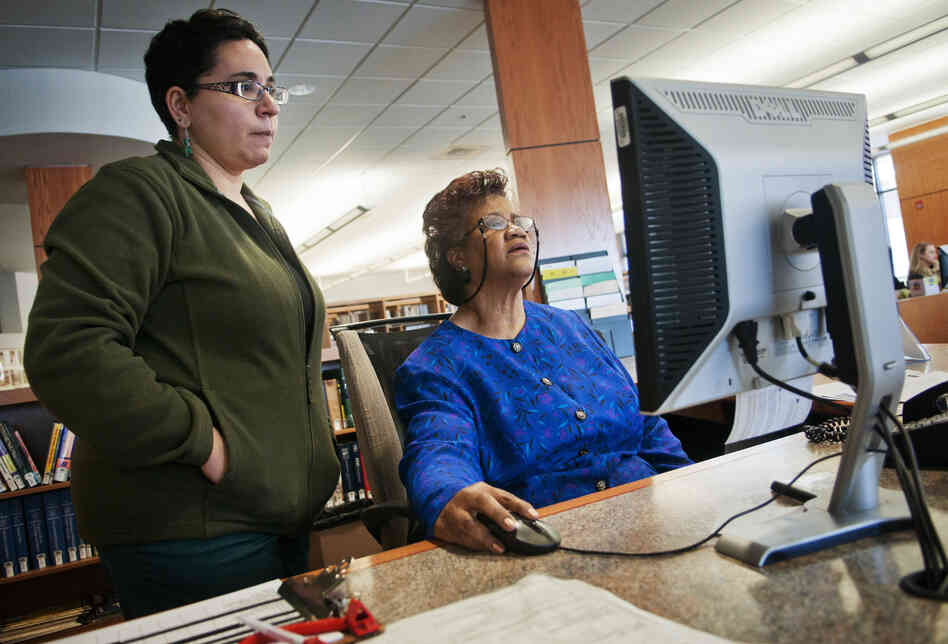 Sims-Wood goes over computer data with librarian Maria Bonet. Though Sims-Wood is on the job at a time when she thought she would be retired, she stays positive. "I have faith that things will work out. I don't care how bad they are. It's going to work out," she says.