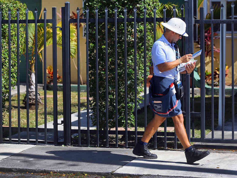 A mailman for the U.S. Postal Service delivers mail on November 15, 2012 in Miami, Florida.