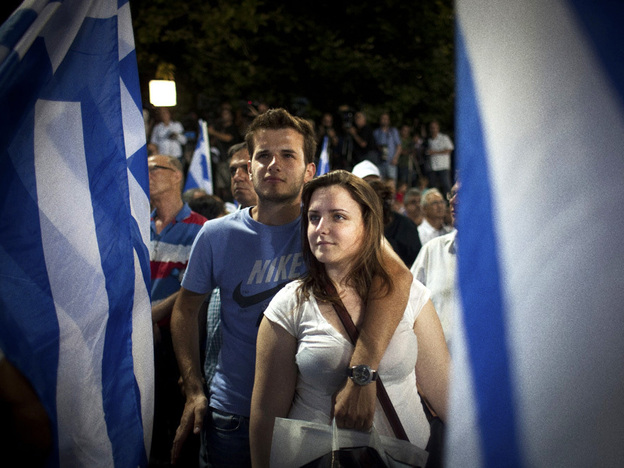 A young couple is framed by Greek flags while watching Antonis Samaras, now the country's prime minister, speak at a campaign rally last June. Samaras wants to dismantle a law making it easier for second-generation Greeks to obtain citizenship.