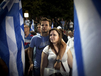A young couple is framed by Greek flags while watching Antonis Samaras, now the country's prime minister, speak at a campaign rally last June. Samaras wants to dismantle a law making it easier for second-generation Greeks to obtain citizenship.