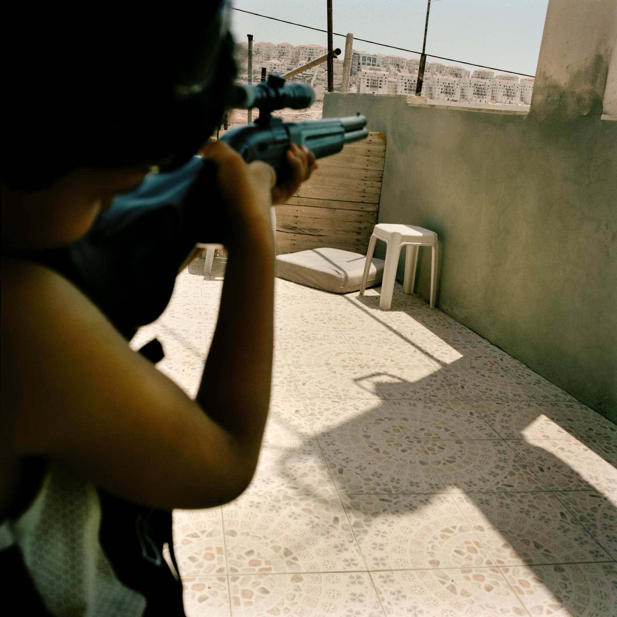 A Palestinian boy from Wadi Fuqin aims a toy gun at the Beitar Illit settlement.