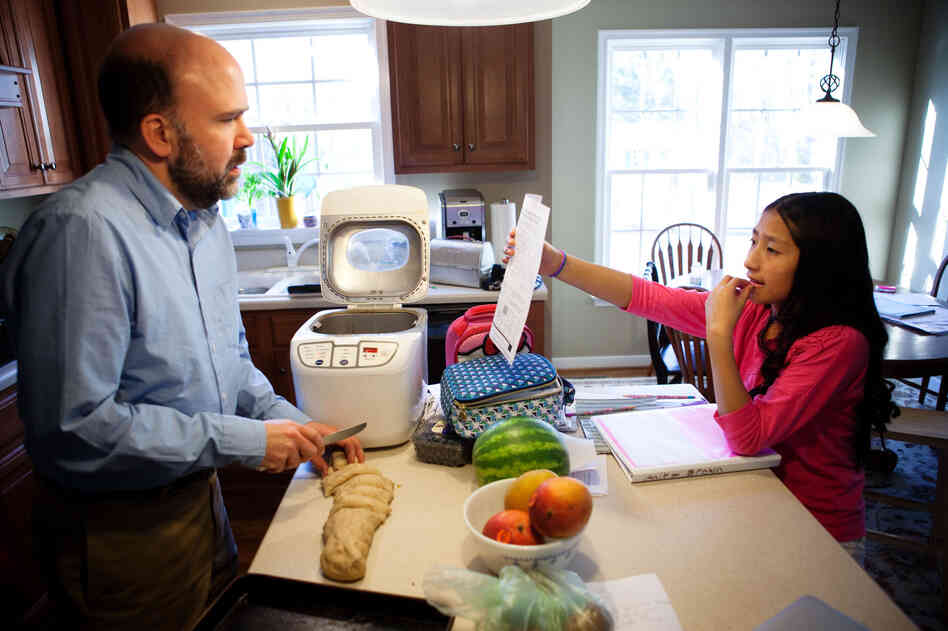 Brown makes dinner rolls while helping his seventh-grader, Anita, with math homework.