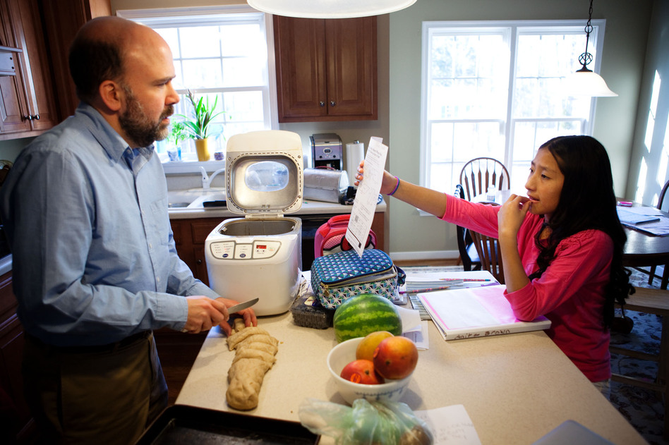 Brown makes dinner rolls while helping his seventh-grader, Anita, with math homework.