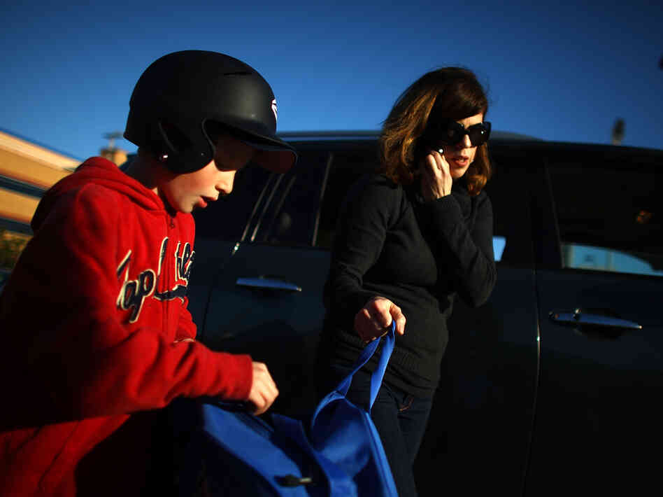 Yvonne Condes helps her son Alec get ready for baseball practice.