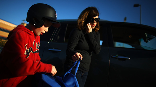 Yvonne Condes helps her son Alec get ready for baseball practice.