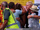 People grieve outside New Zealand's Muriwai Surf Lifesaving Club after the fatal shark attack at Muriwai Beach on Wednesday.