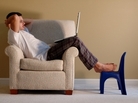 Man sitting on a club chair reading from his laptop. Man sitting on a club chair reading from his laptop.