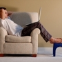 Man sitting on a club chair reading from his laptop.