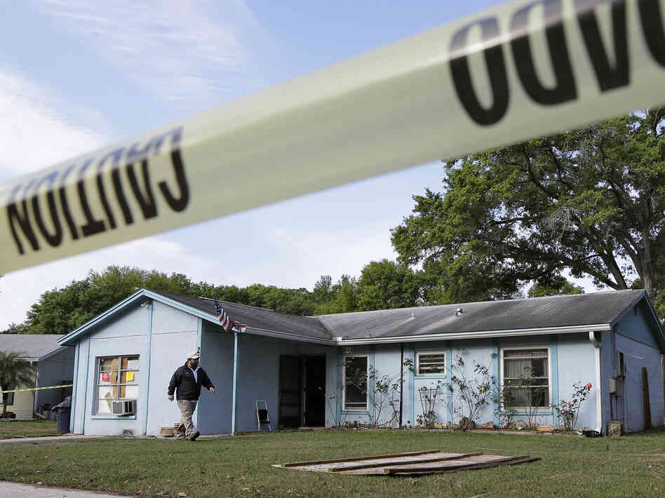 An engineer surveys in front of the home where a sinkhole opened up late Thursday near Tampa, Fla. A man who had been in one of the home's bedrooms screamed for help and disappeared. It's feared he died.