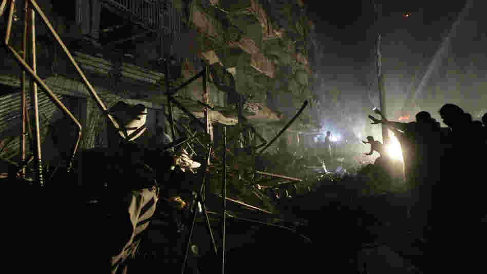 Pakistanis check the site of a bomb blast in Karachi on Sunday. Pakistani officials say the blast has killed dozens of people in a neighborhood dominated by Shiites.